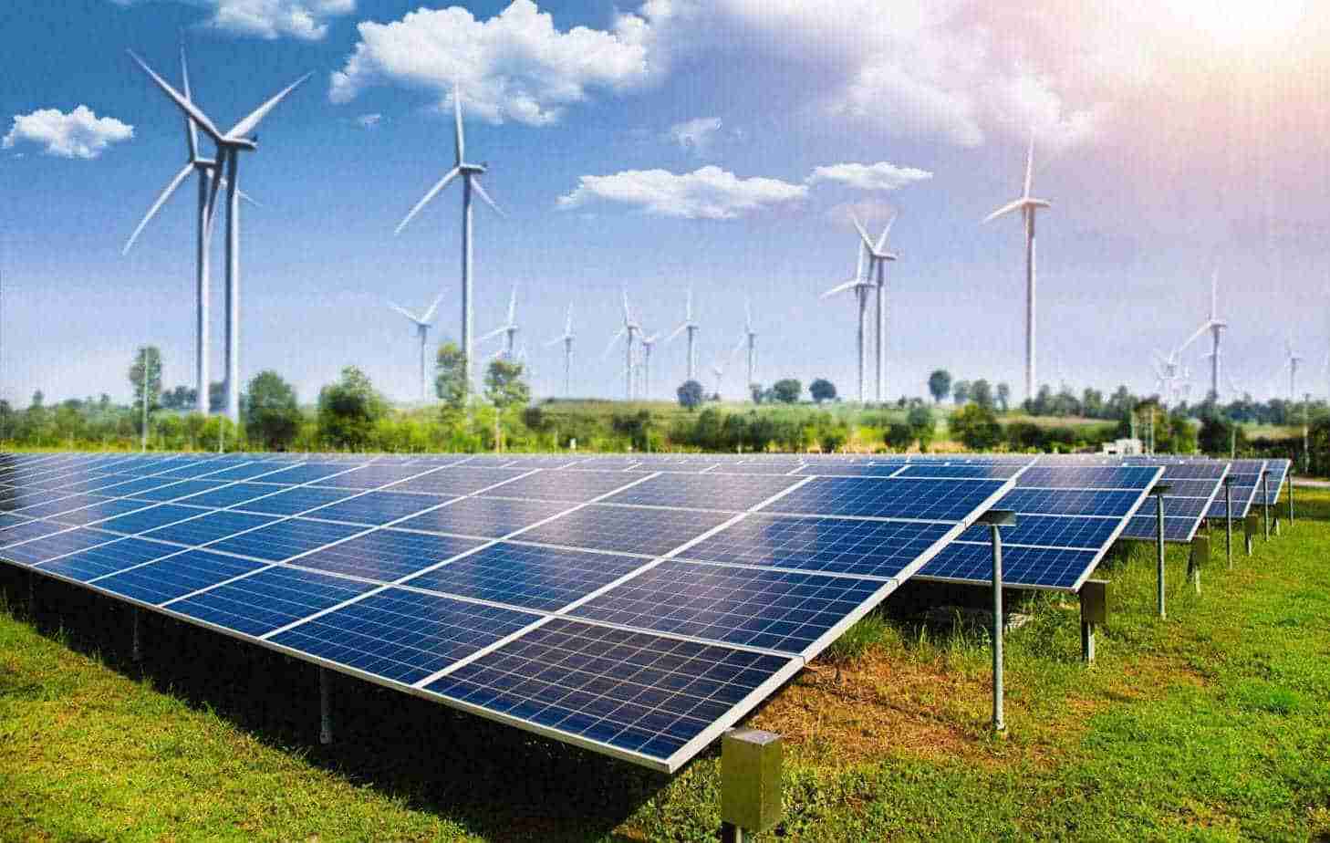 solar panel with wind turbines against mountains and sky as back